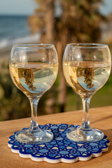 Glasses of Spanish dry white wine served on andalusian style board with blue ornament on beach terrace with view on Mediterranean sea