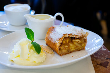 Austrian sweet dessert, portion of apple strudel with whippen cream and hot vanilla sauce served in...