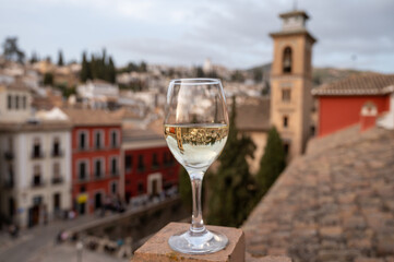 Glass of Spanish dry rueda white wine served on roof terrace with view on old part of Andalusian town Granada, Spain