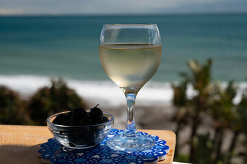 Spanish dry rueda white wine and black olives tapas served on beach terrace with view on...