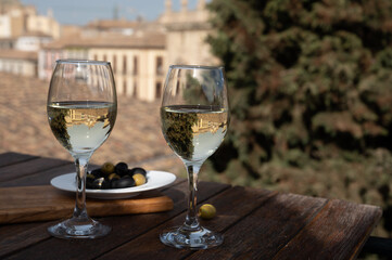 Two glasses of Spanish dry rueda white wine served with olives on roof terrace with view on old part of Andalusian town Granada, Spain