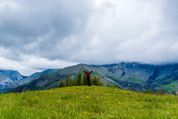 A wide angle shot of a young female hiker on a break during a hike on a cloudy summer day in the French Alps (Valberg, Alpes-Maritimes, France)