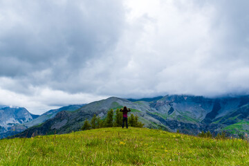 A wide angle shot of a young female hiker on a break during a hike on a cloudy summer day in the French Alps (Valberg, Alpes-Maritimes, France)