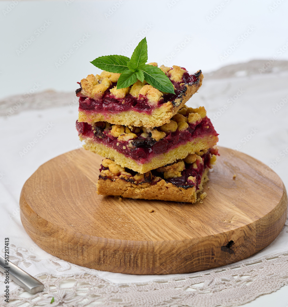 Poster square slices of cherry crumble lie in a stack on a white background.