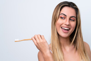 Young caucasian woman isolated on white background with a toothbrush and surprised expression