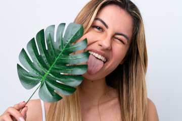 Young caucasian woman isolated on white background holding a palm leaf with happy expression. Close up portrait