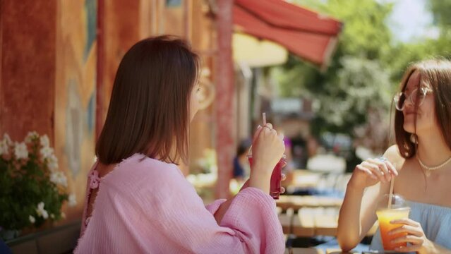 two young women girlfriends enjoy delicious cocktails in a cafe, spend time in a place, lifestyle in summer.