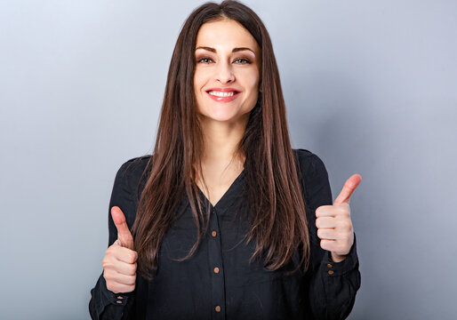 Beautiful long hair toothy smiling woman showing the hands the fingers thumb up, the ok sign on light blue studio background. Closeup