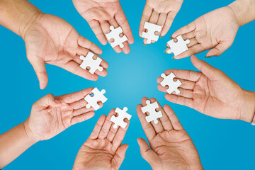 Close up Businesspeople hand holding jigsaw puzzle in a circle on the table on blue background, success and strategy concept.