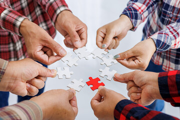 Close up Businesspeople hand holding jigsaw puzzle in a circle on the table, success and strategy concept.