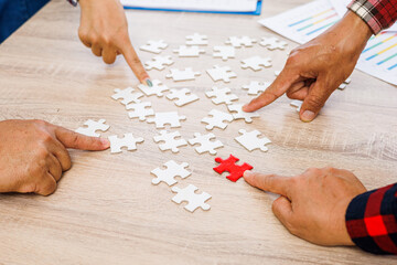Close up Businesspeople hand holding jigsaw and jigsaw puzzle on the table, success and strategy concept.