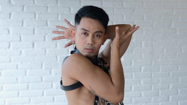 A sensual guy in a leather suit with chains expressively shows vogue poses. People's lives are not of traditional sexual orientation. A transgender loves himself for who he is. Homosexual model.