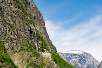 Large waterfall that rises in the mountains surrounded by green trees in Norway.