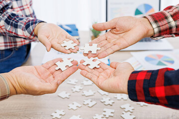 Close up Businesspeople hand holding jigsaw puzzle in a circle on the table, success and strategy concept.