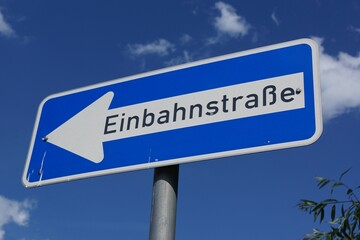 A one-way street sign against a blue sky in Germany