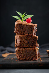 Baked pieces of chocolate brownie pie on black table, delicious dessert