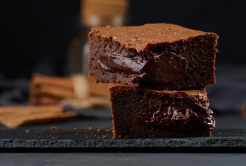 Baked pieces of chocolate brownie pie on black table, delicious dessert