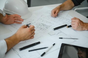 two people sit in front of construction plan and talk about the architecture
