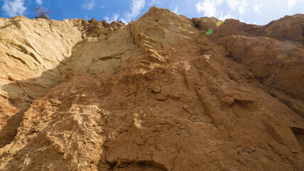 Ruined clay slope on the coast. Cracked clay cliff on the coast. A crumbling and cracked clay wall.