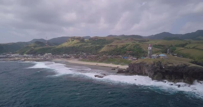 Drone footage of the ocean and the Basco Lighthouse on the shore in Batanes, Philippines