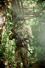 Soldier of the Ukrainian army with a machine gun and a helmet in the forest