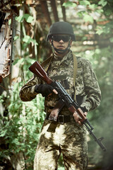 Soldier of the Ukrainian army with a machine gun and a helmet in the forest