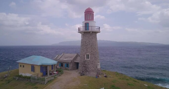 Drone footage of  Lighthouse and small buidlings on the shore in Batanes, Philippines