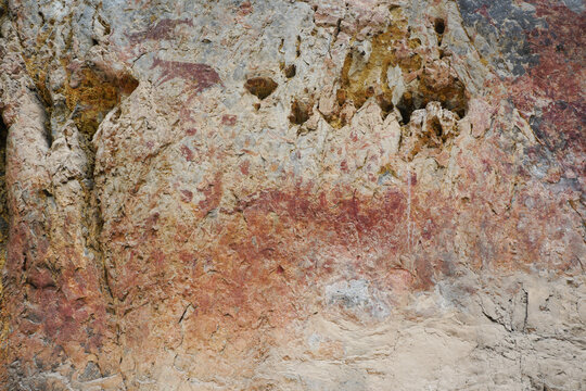 The texture of Limestone cliffs with ancient wall paintings of  Mountain Goat, fingers, and hands. The archaeological site of color paintings of Pratu Pha Volley of Lampang, Thailand.