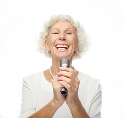Happy senior woman with curly hair singing with microphone, having fun, expressing musical talent