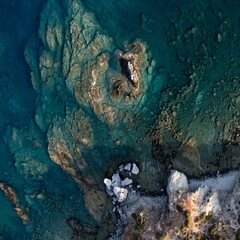 Aerial top view of a turquoise sea near a rocky coast in Greece