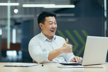 A happy young man Asian businessman freelancer conducts a video conference from a laptop with...