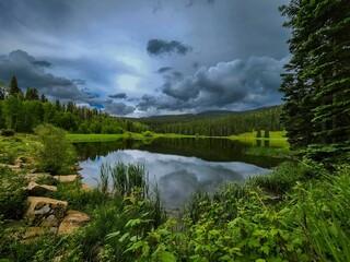 Beautiful view of Henderson Lake surrounded by trees under a cloudy sky in Colorado