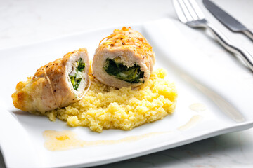 poultry roulade filled with spinach and cheese served with couscous