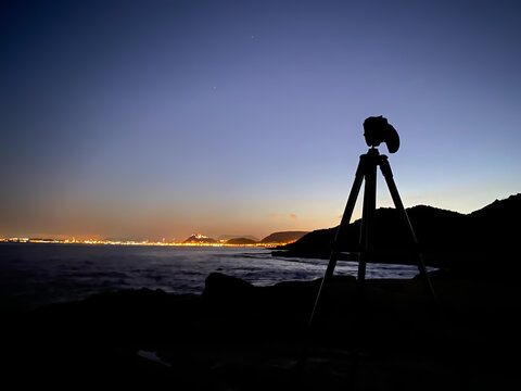 Photos of a camera on a tripod taking pictures at sunrise on the beach, because it is the photography day.