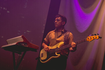 Young latino bassist and keyboardist with shirt and glasses, and cream bass and vintage keyboard...
