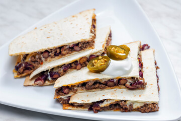 quesadilla filled with minced beef meat, beans and cheese