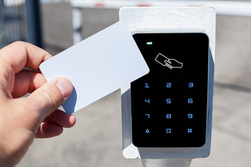 The client touches with a white plastic card the card reader for access cards to enter the parking...