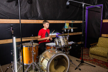 Fototapeta premium a young drummer plays drums, cymbals with sticks, sitting on a special chair