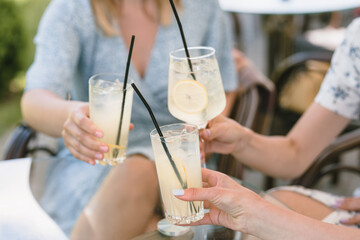 Friends having lemonade drinks on outdoors terrace. Summer lifestyle.
