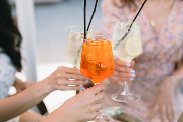 Women holding glasses of summer cocktails. Sunny summer day.