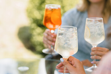 Women holding glasses of summer cocktails. Friends enjoying summer outdoors. Copy space.