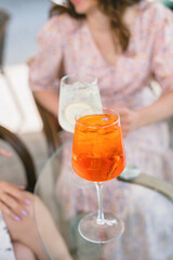 Summer aperol cocktail on table. Friends having drinks in cafe together. Lifestyle concept....