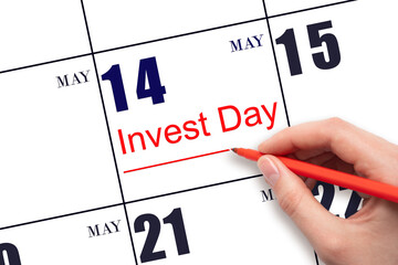 Hand drawing red line and writing the text Invest Day on calendar date May 14. Business and...