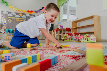 Toddler boy playing with wooden train in kindergarten