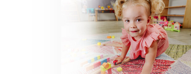 Toddler girl playing with wooden blocks in kindergarten