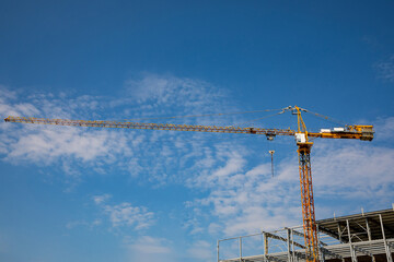 Construction crane on a background of blue sky on a sunny day lifts loads.