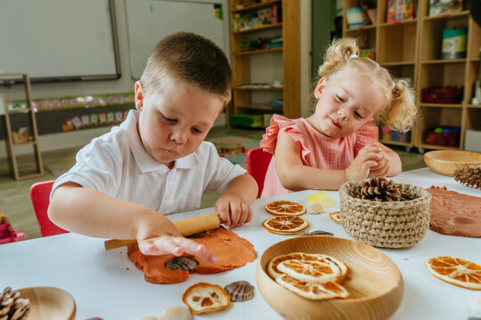 Children make prints on the dough using natural materials