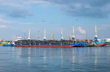 River port. A barge with a tug boat standing for loading. Port cranes