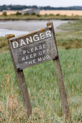 Old wooden sign on a creek in Essex warning of people to keep off the mud