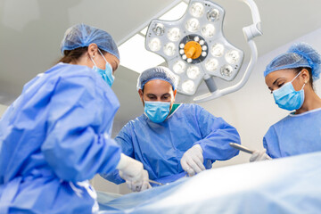 Surgeons doing surgery in operating theatre. Male and female surgeons operating patient. Medical...